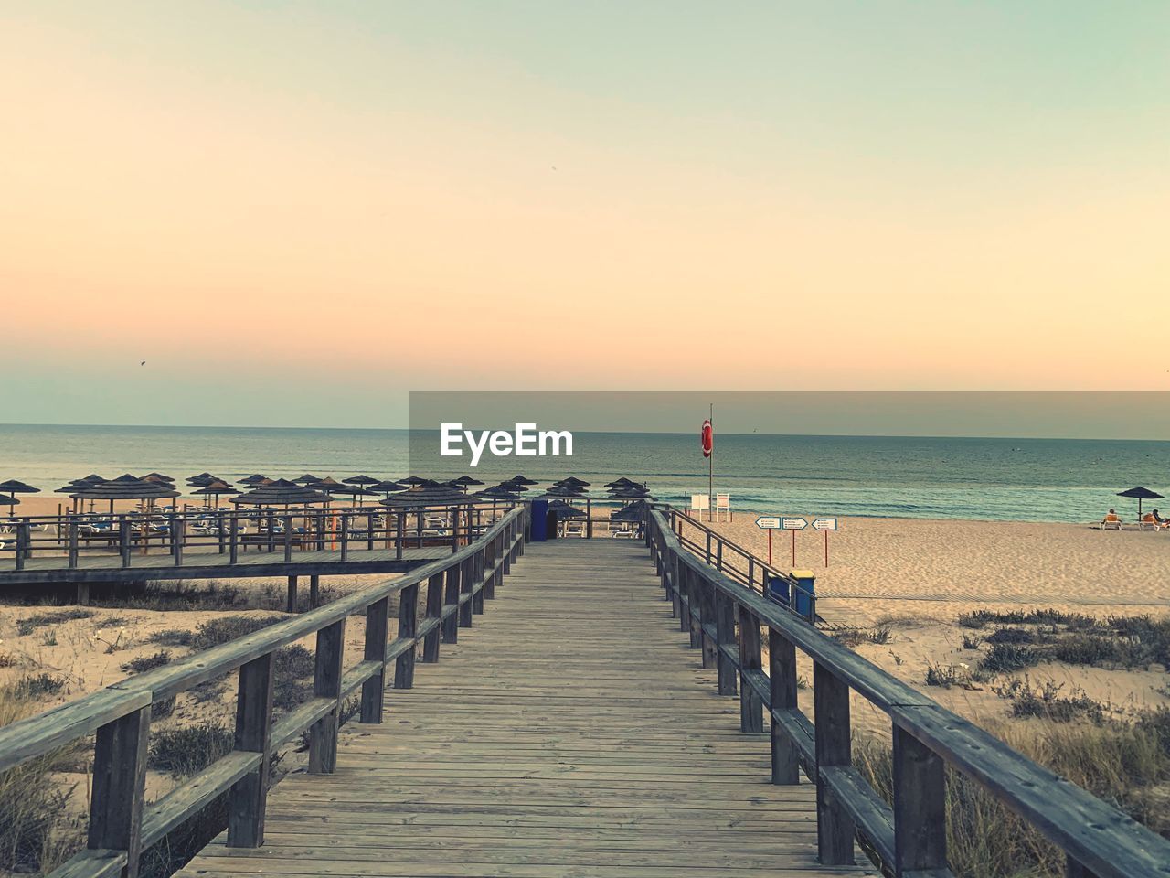 Pier over sea against sky during sunset