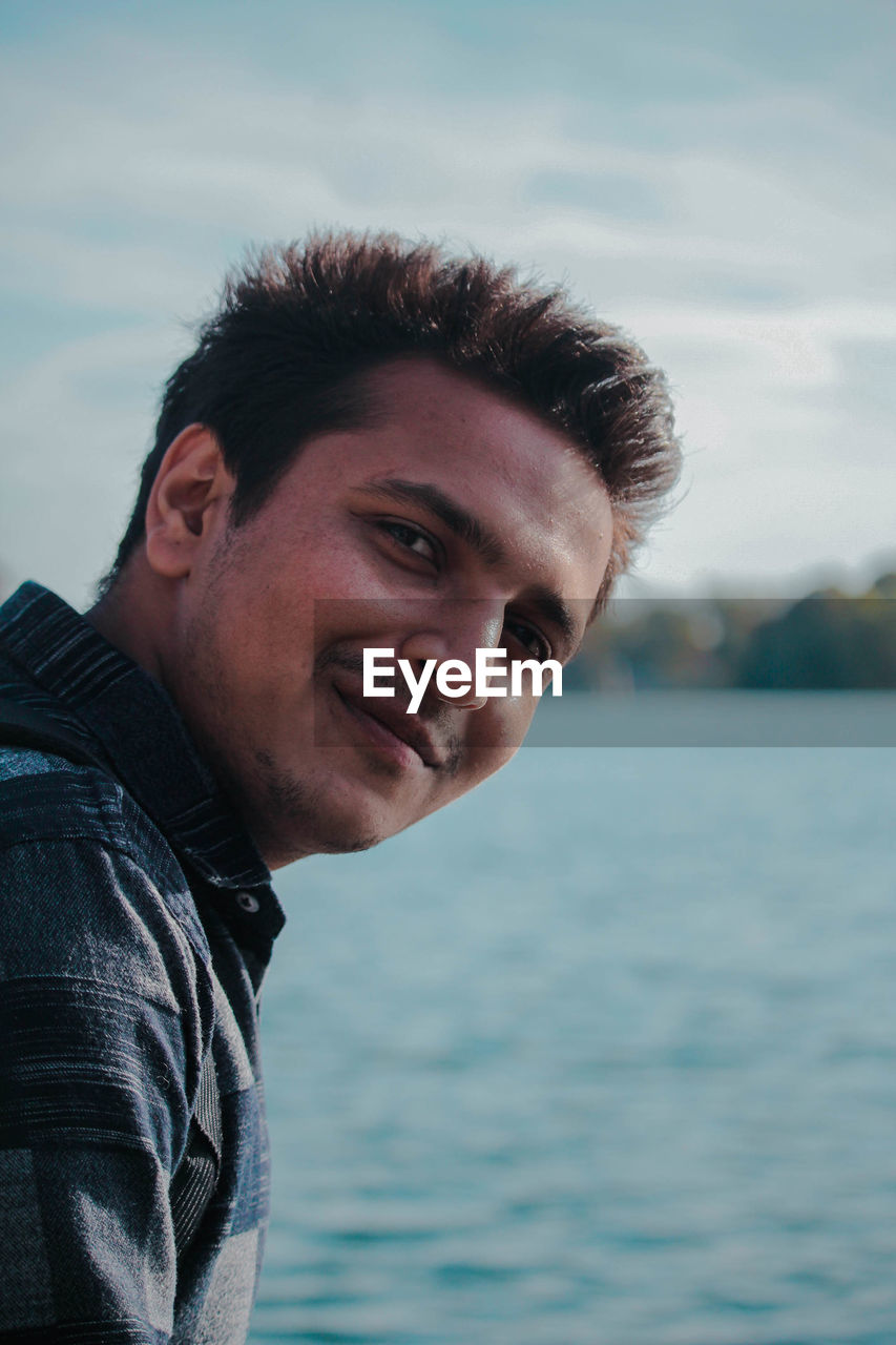 Portrait of young man against sky