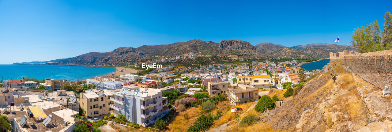 high angle view of townscape by mountain against clear blue sky