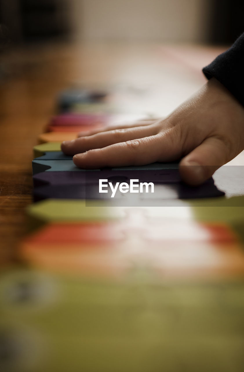 Preschooler boy's hand putting together a brightly colored puzzle