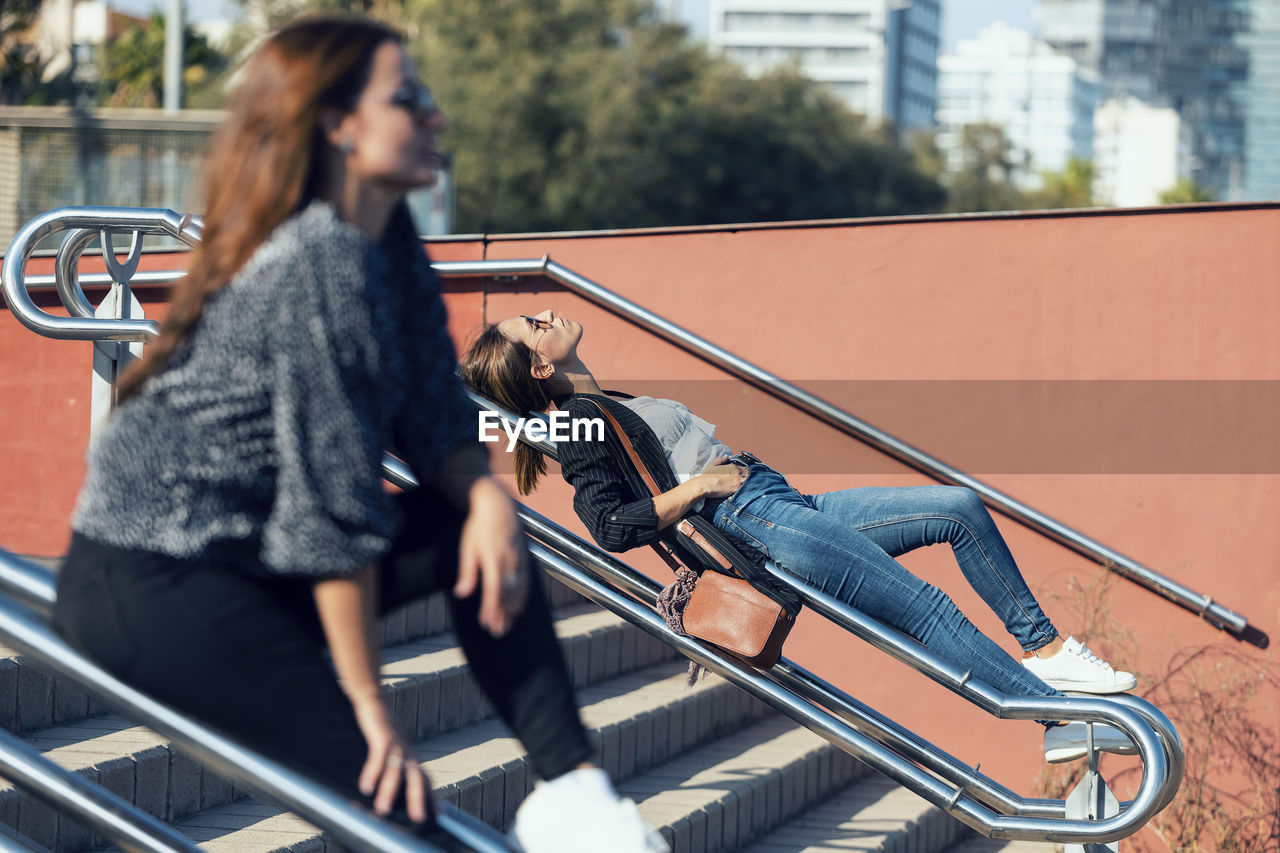 Women relaxing on railing of staircase in city