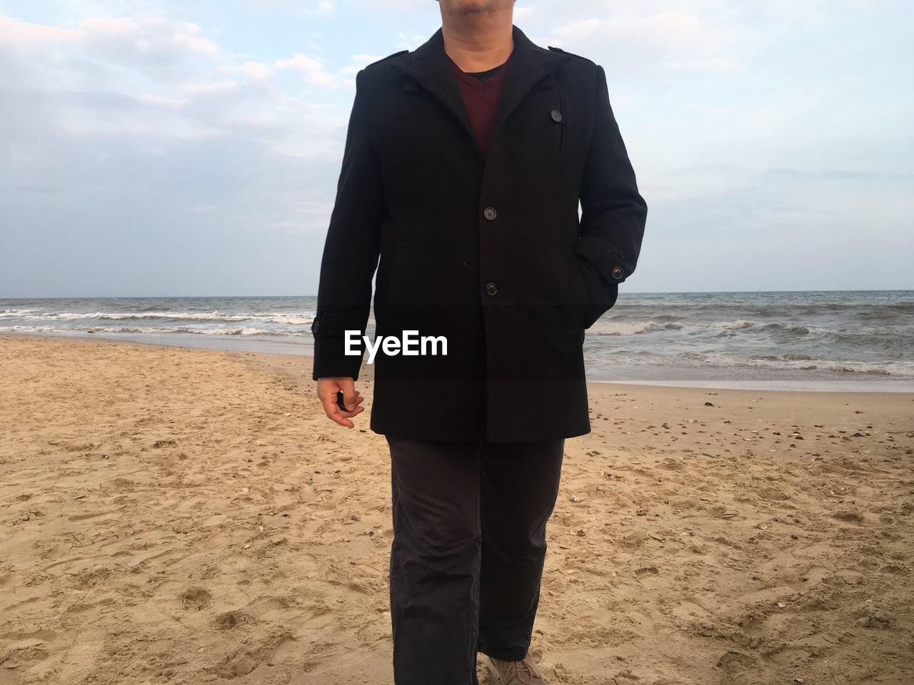 MIDSECTION OF MAN STANDING ON BEACH