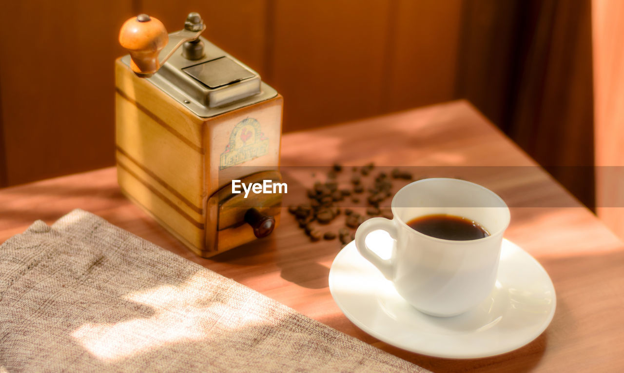 CLOSE-UP OF COFFEE CUP AND SPOON ON TABLE