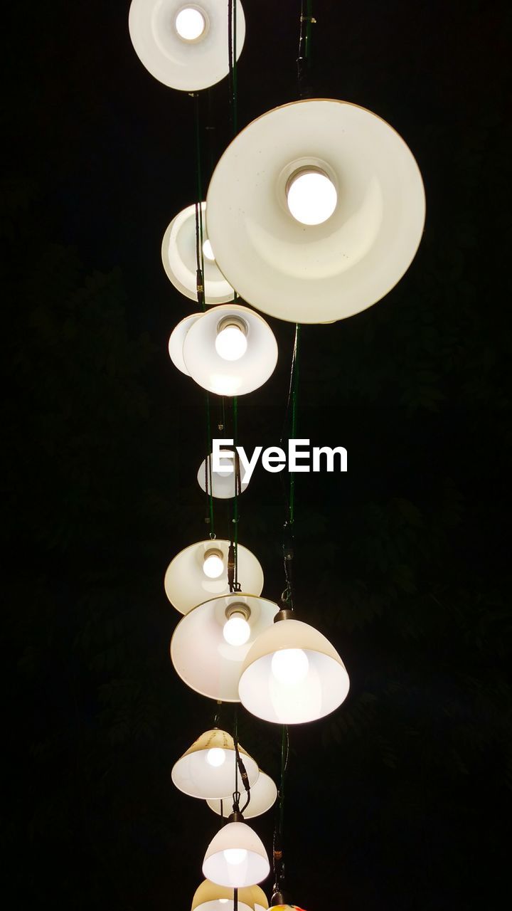 Low angle view of illuminated pendant lights hanging at night