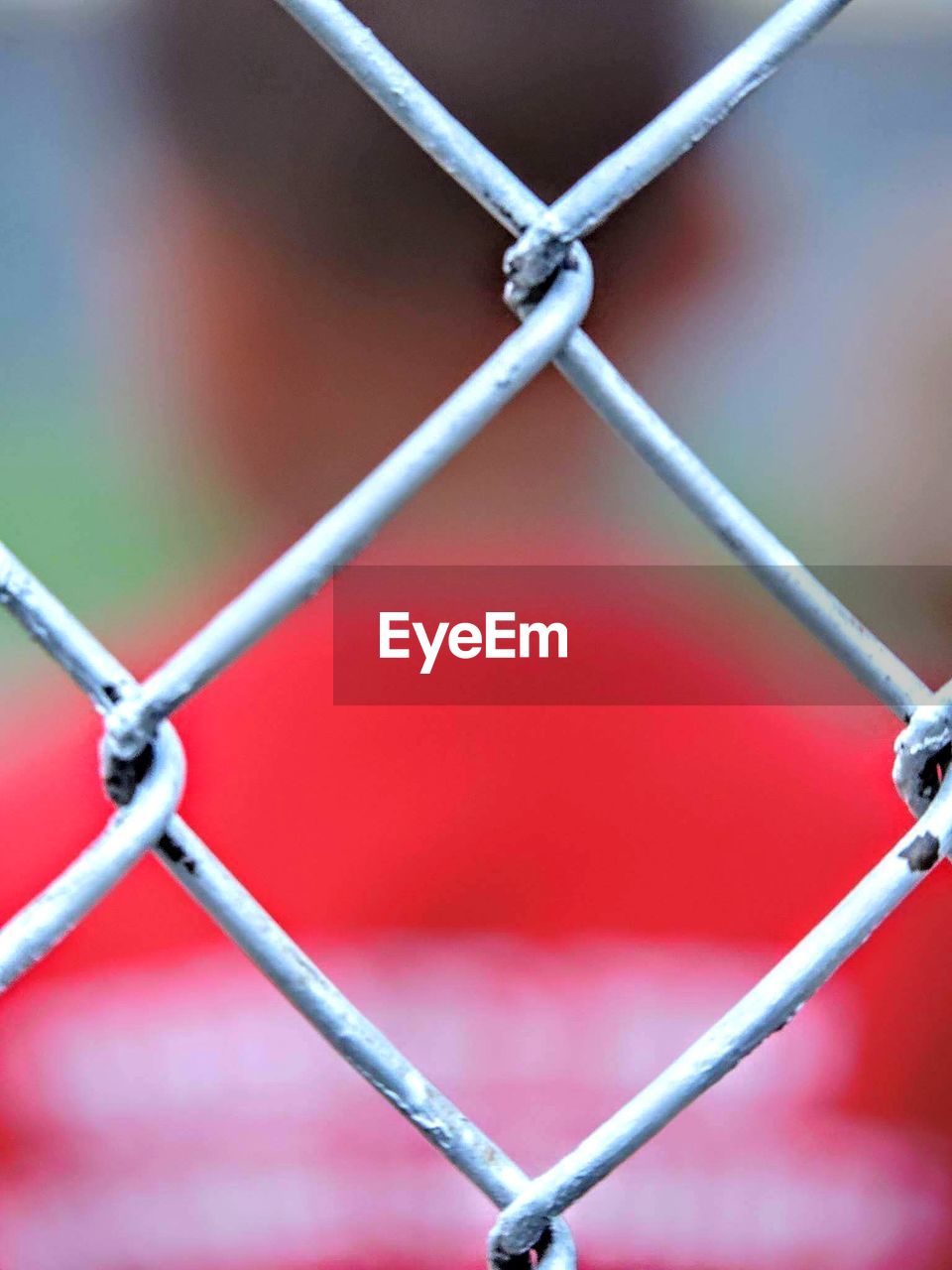 CLOSE-UP OF CHAINLINK FENCE AGAINST BLURRED BACKGROUND