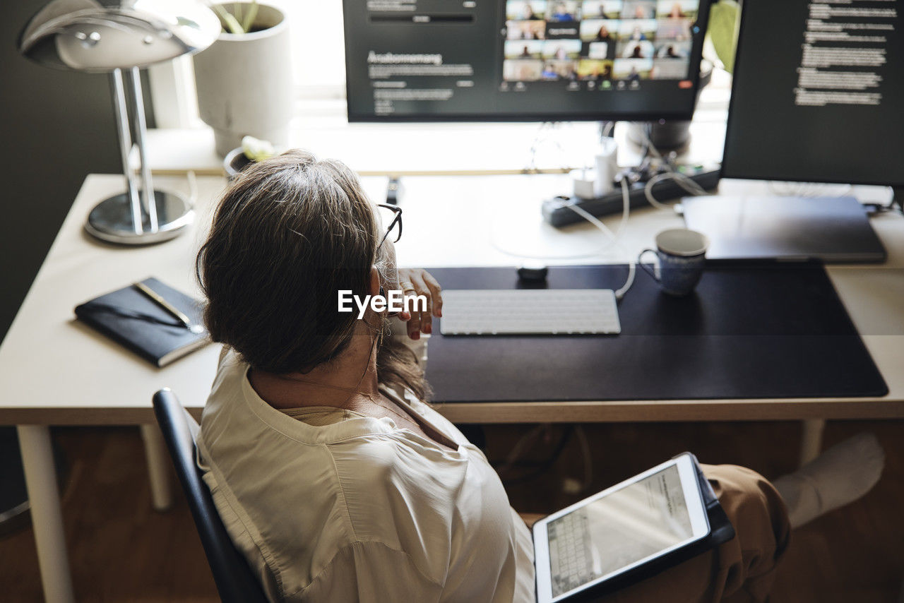 High angle view of freelancer sitting with tablet pc at desk in home office