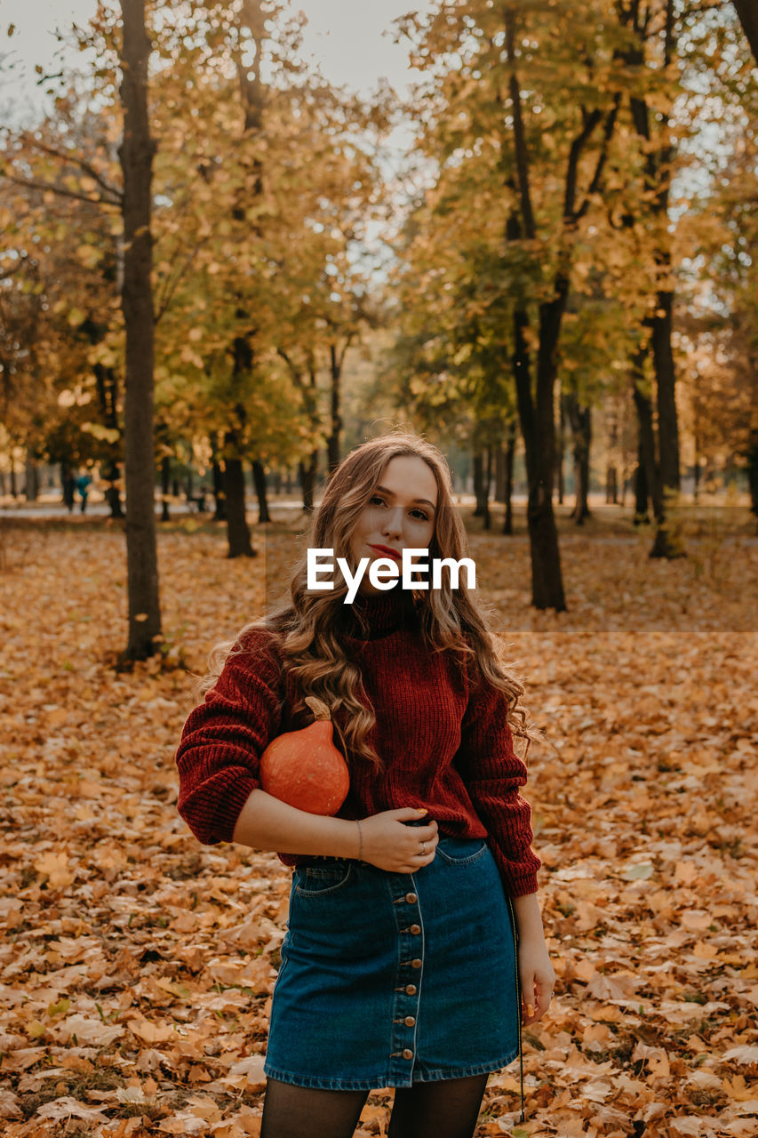 Beautiful young woman standing in park during autumn