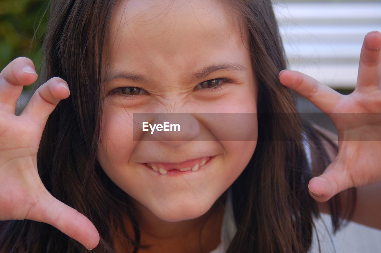 CLOSE-UP PORTRAIT OF A SMILING GIRL WITH HANDS