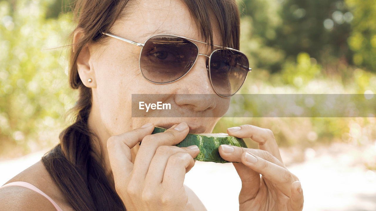 Close-up portrait of woman eating watermelon at beach