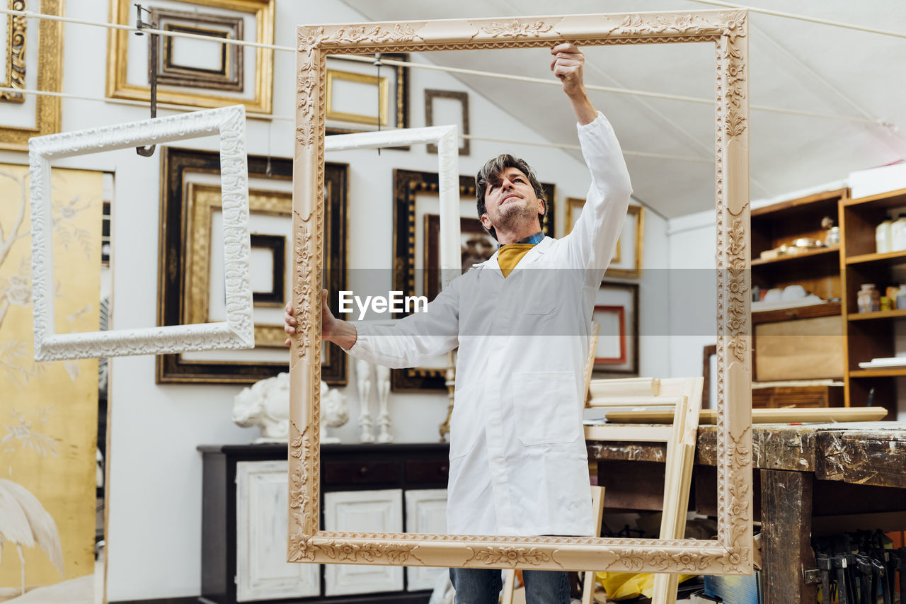 Mature craftsman examining frame at workshop