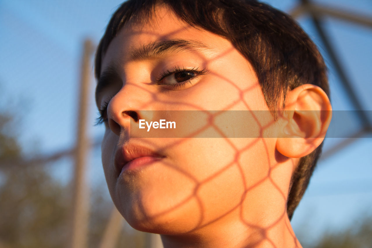 Close up portrait of boy with fence shadow 