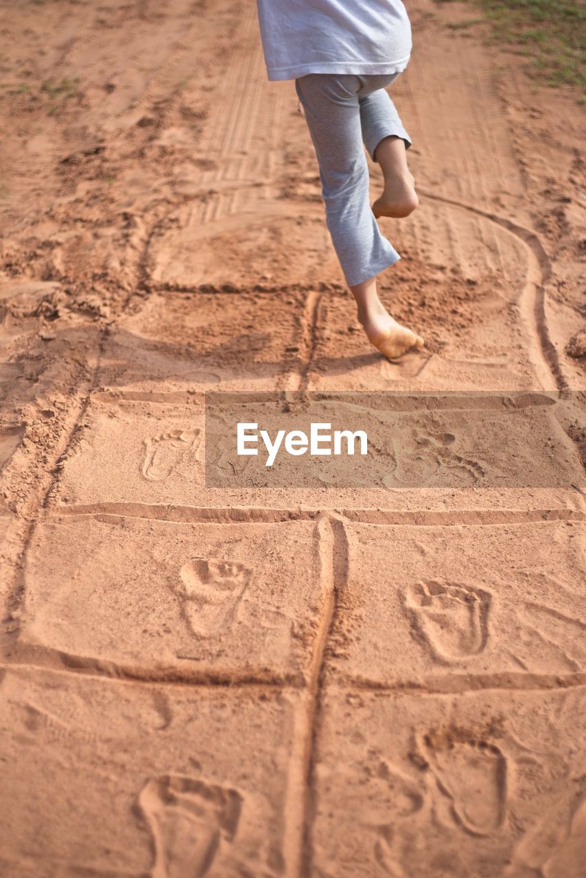 Low section of child playing hopscotch on sand