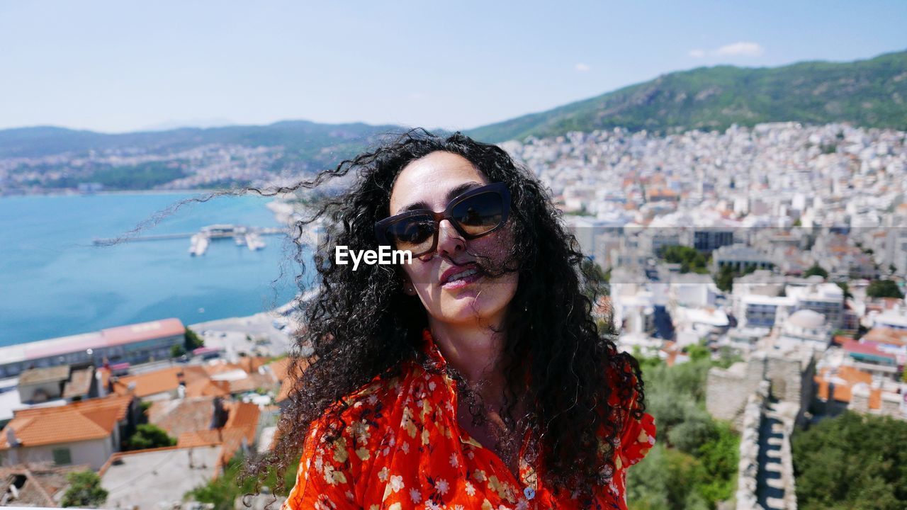 Portrait of woman wearing sunglasses against city