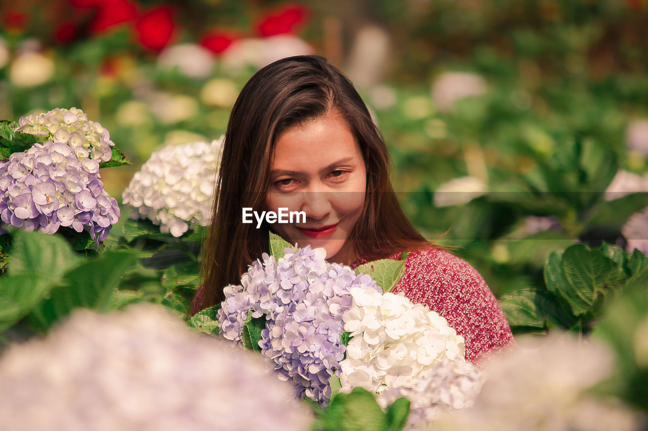 PORTRAIT OF SMILING WOMAN WITH PINK FLOWER