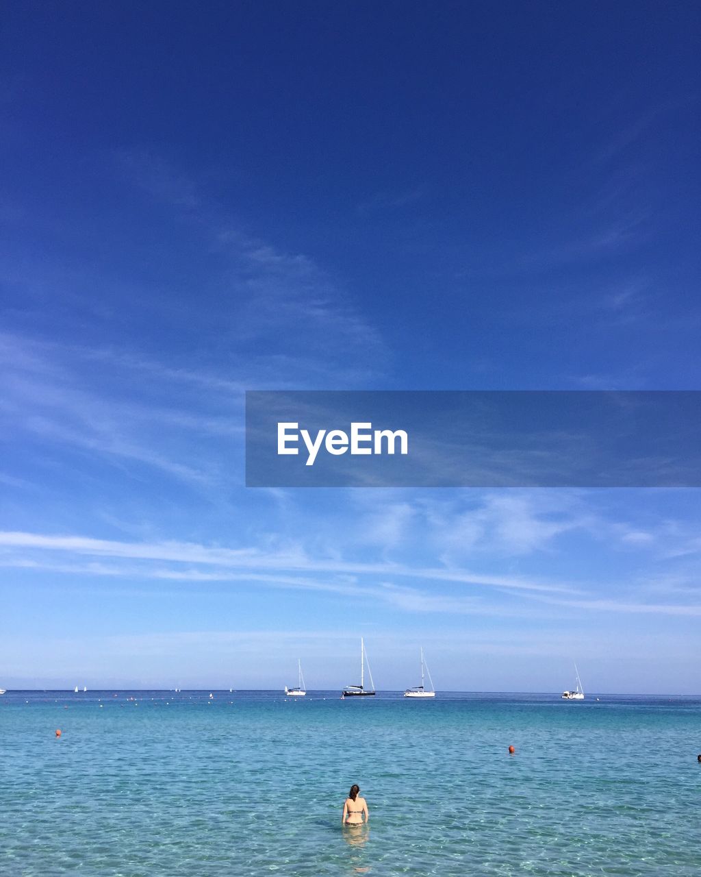 Rear view of woman standing in sea against sky