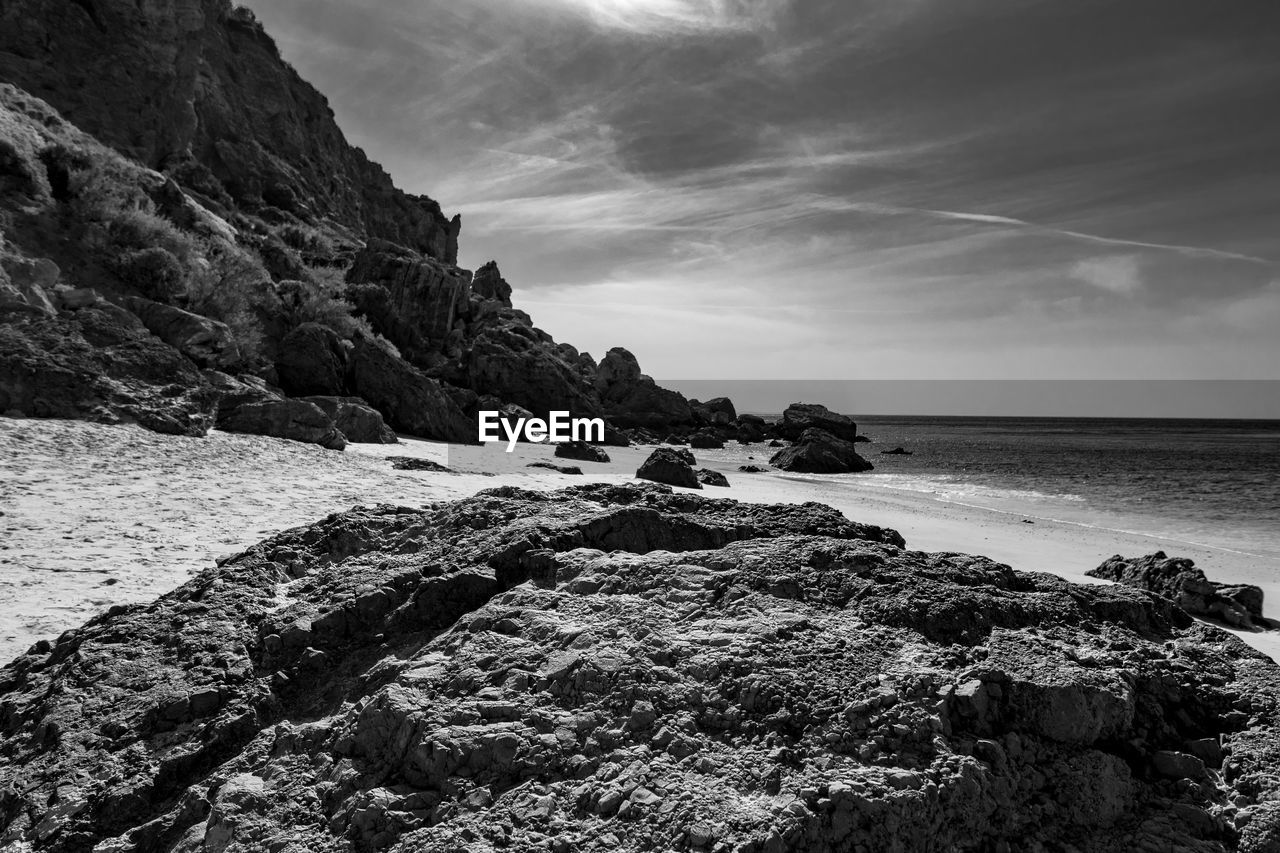 Rock formation on beach against sky