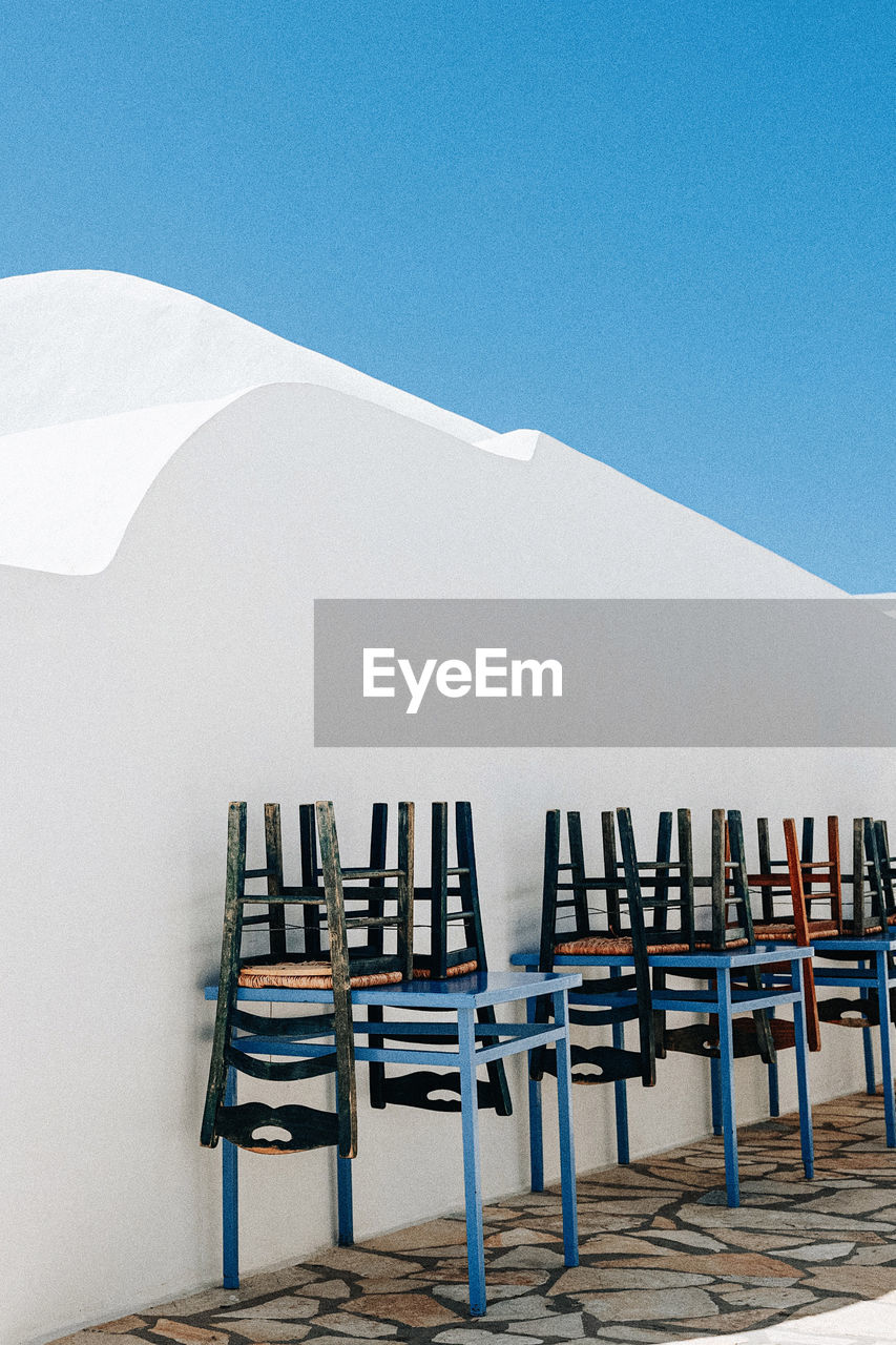 Low angle view of a greek islands alley with chairs and tables 