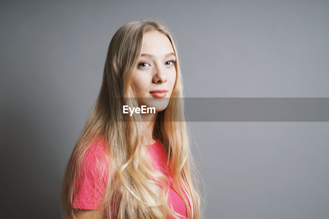 Portrait of smiling teenage girl against gray background