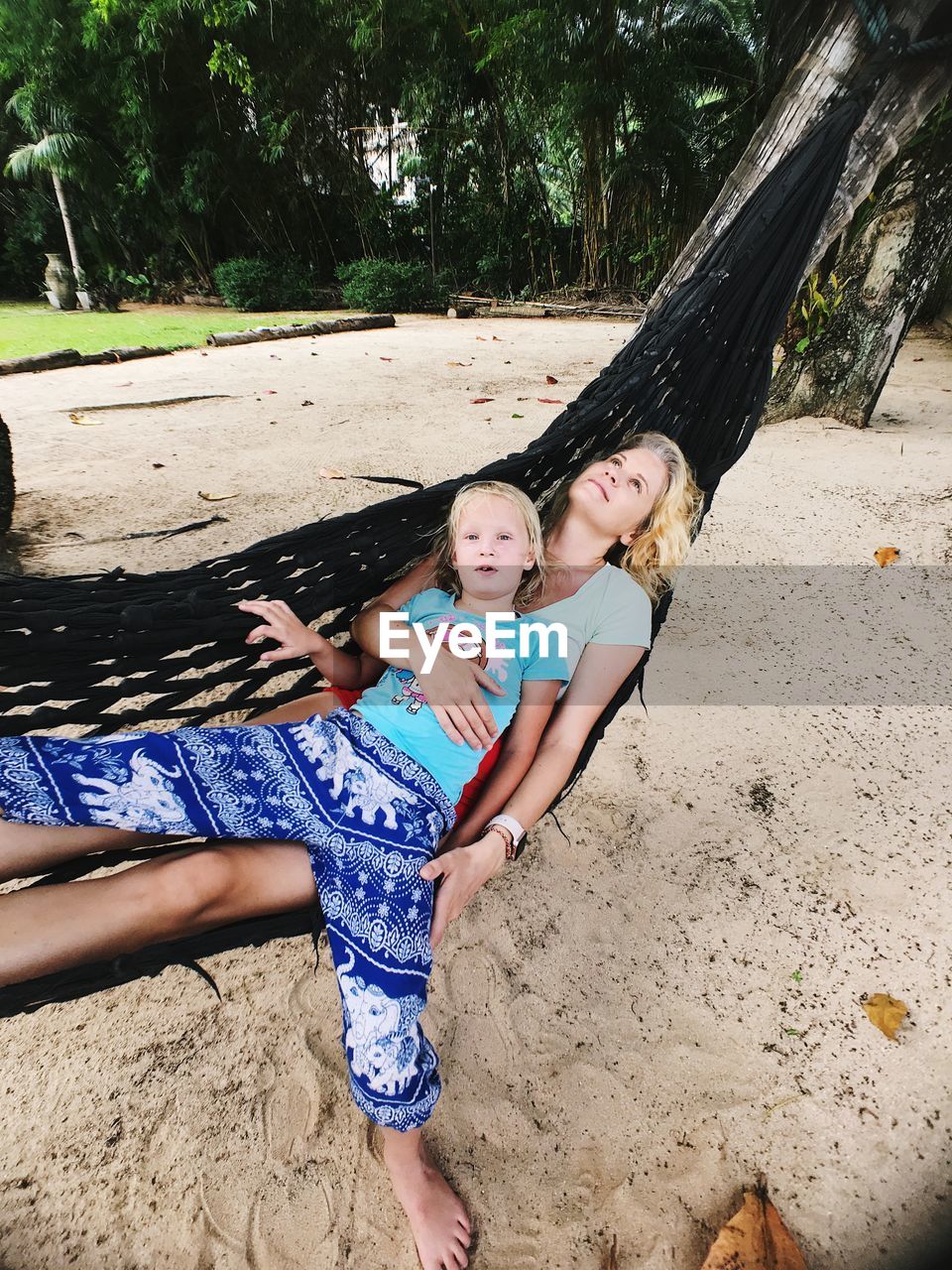 High angle view of mother and daughter on hammock at beach