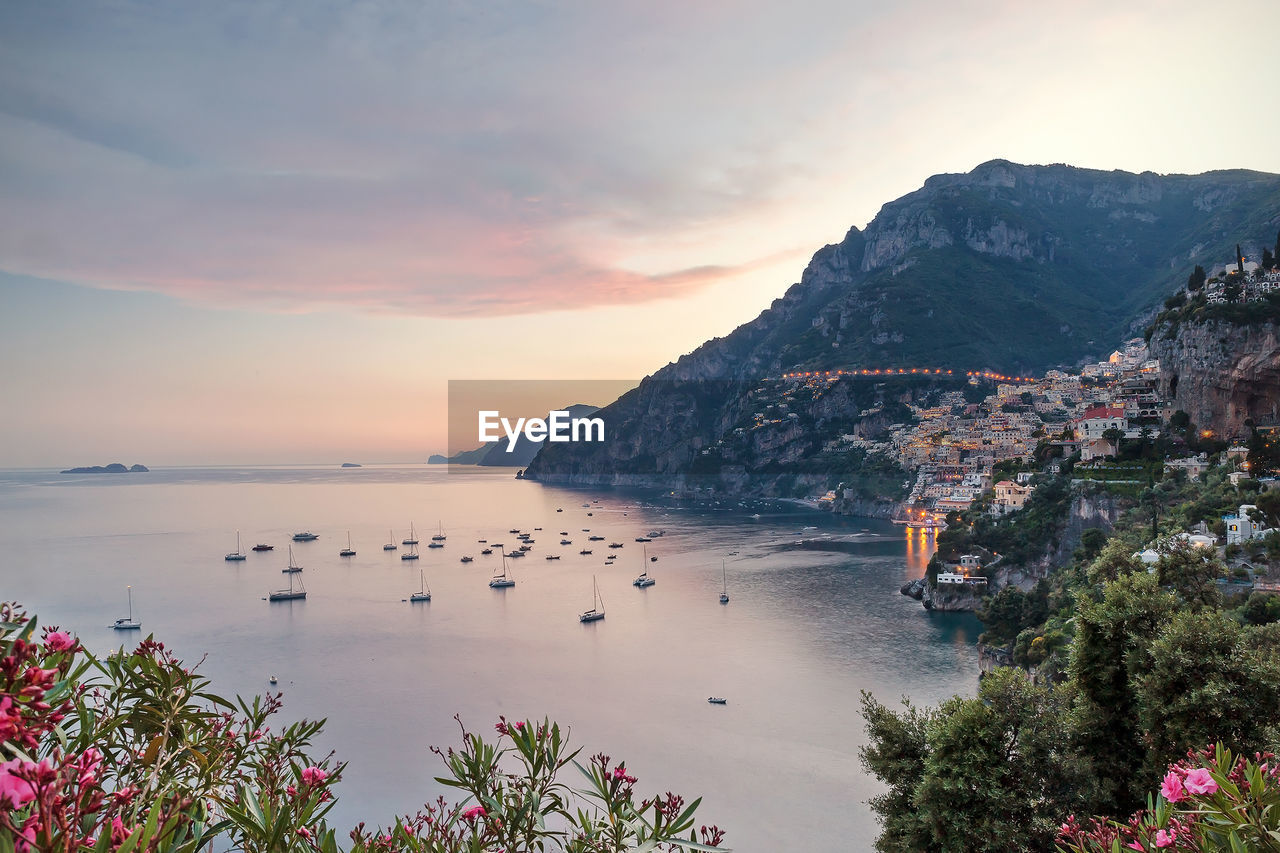 High angle view of sea by mountain against sky at sunset