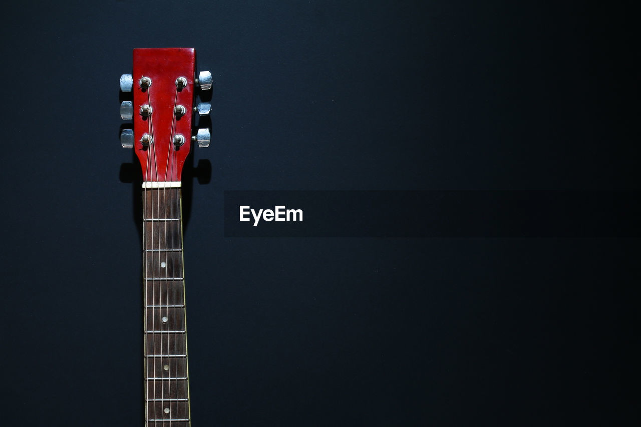 Close-up of acoustic guitar against black background