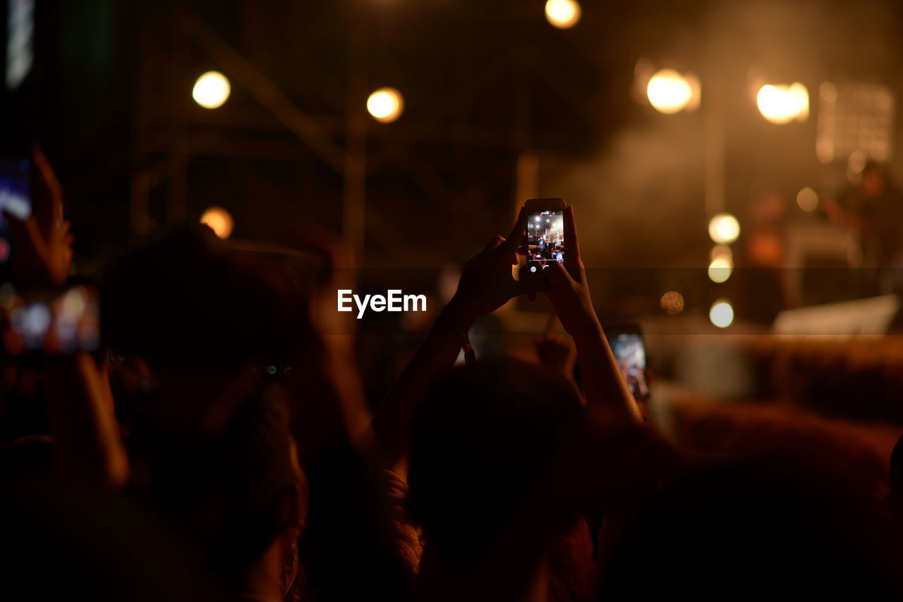 CLOSE-UP OF WOMAN PHOTOGRAPHING ILLUMINATED MUSIC CONCERT
