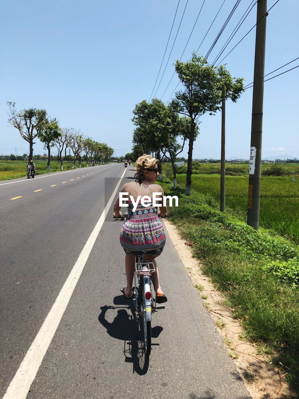 REAR VIEW OF WOMAN RIDING BICYCLE