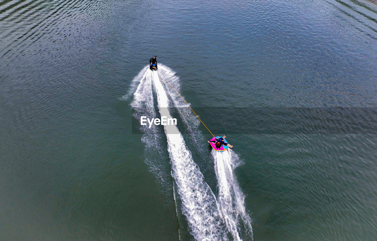 water, high angle view, transportation, nautical vessel, mode of transportation, wake, motion, day, sports, wave pattern, nature, boating, men, water sports, group of people, vehicle, speed, sea, boat, outdoors, on the move, travel, beauty in nature, aerial view, lifestyles, teamwork, cooperation, waterfront