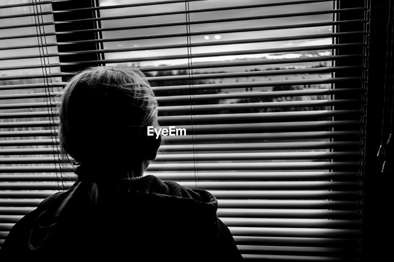 Rear view of girl looking through window