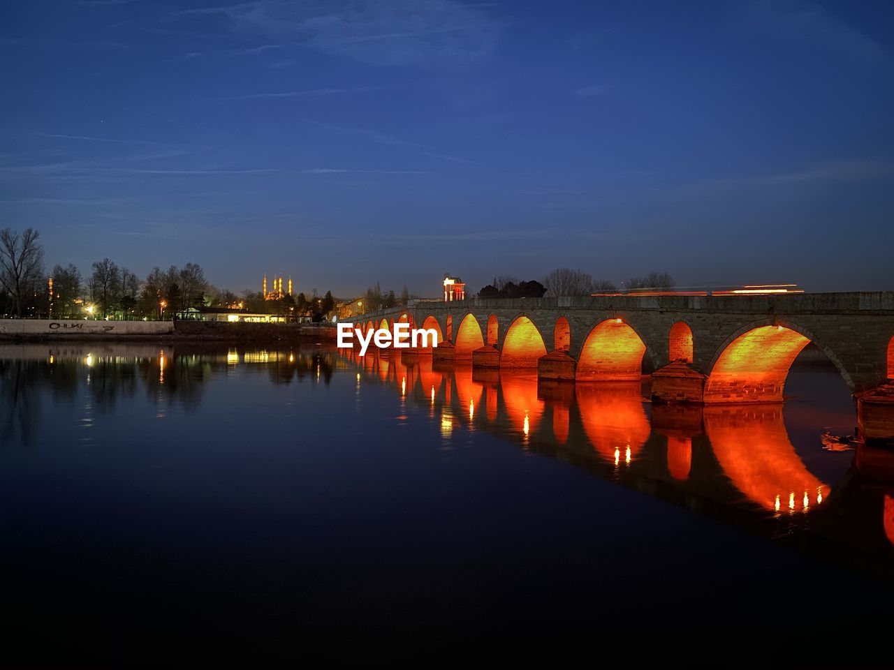 Illuminated bridge over river against sky