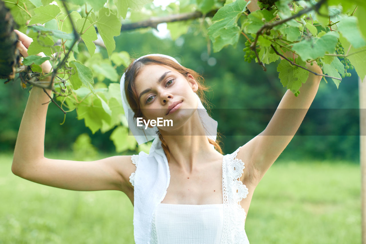 side view of young woman standing by tree