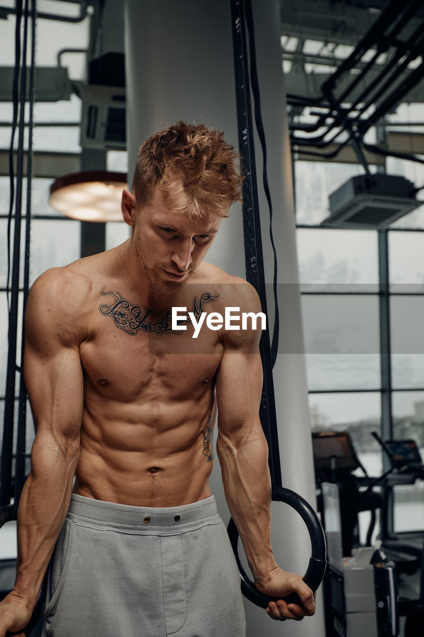 portrait of shirtless man exercising in gym