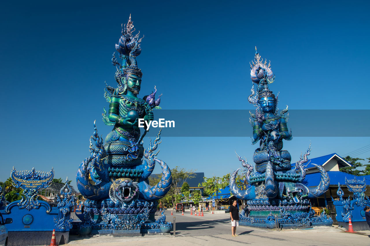 LOW ANGLE VIEW OF SCULPTURES AGAINST BLUE SKY