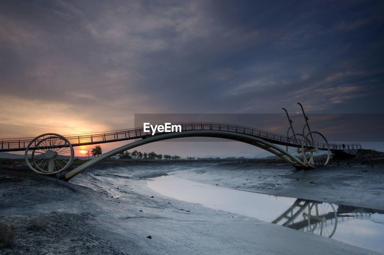 Bridge over river against sky during sunrise