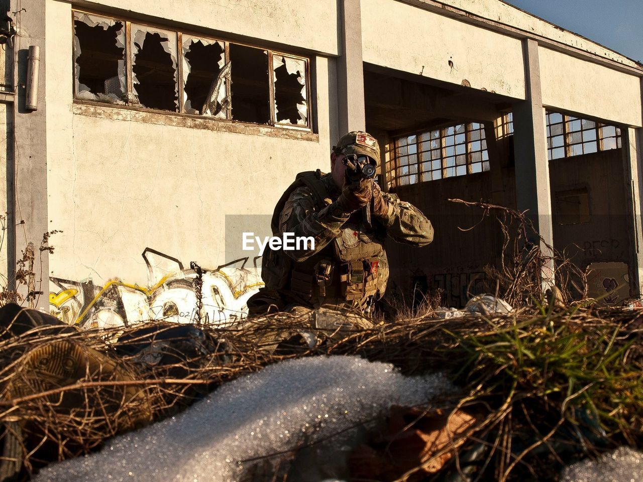 Soldier on field against abandoned building