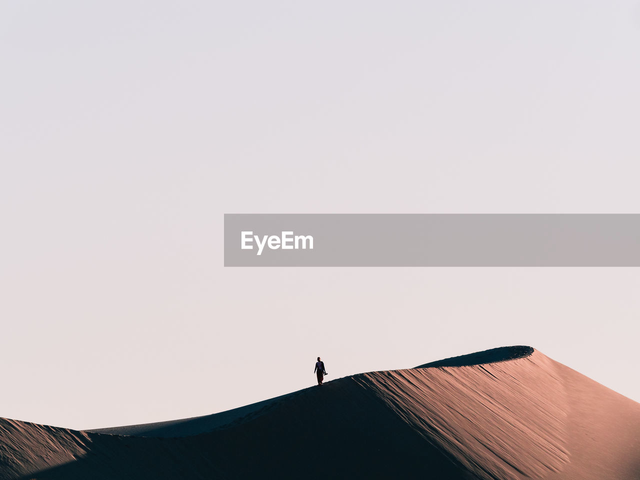 Low angle view of silhouette person standing on sand dune against clear sky