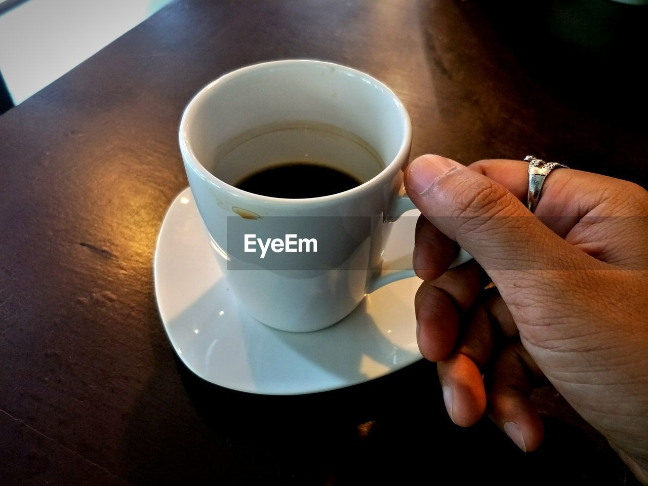 PERSON HOLDING COFFEE CUP AND SPOON