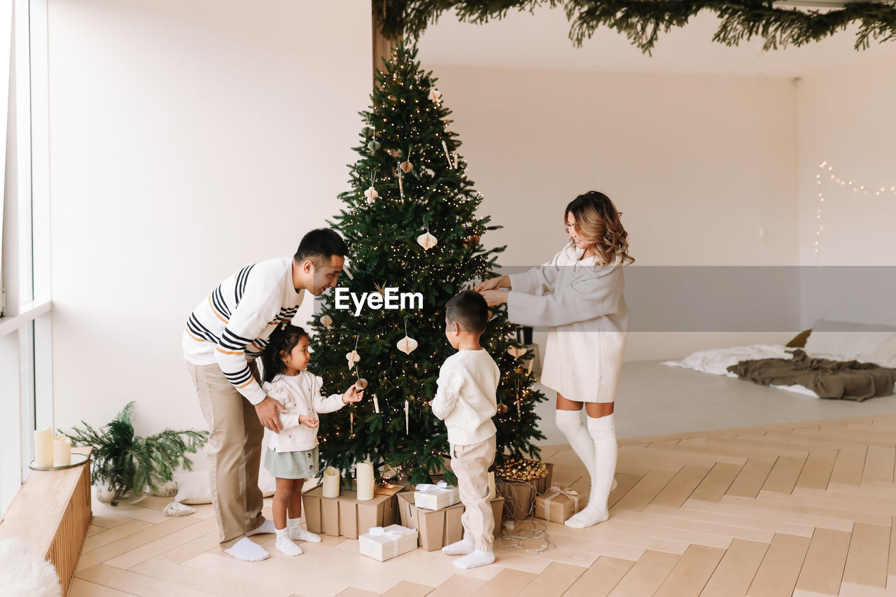 An asian multi-racial family with kids celebrate the christmas holiday in a decorated indoor house
