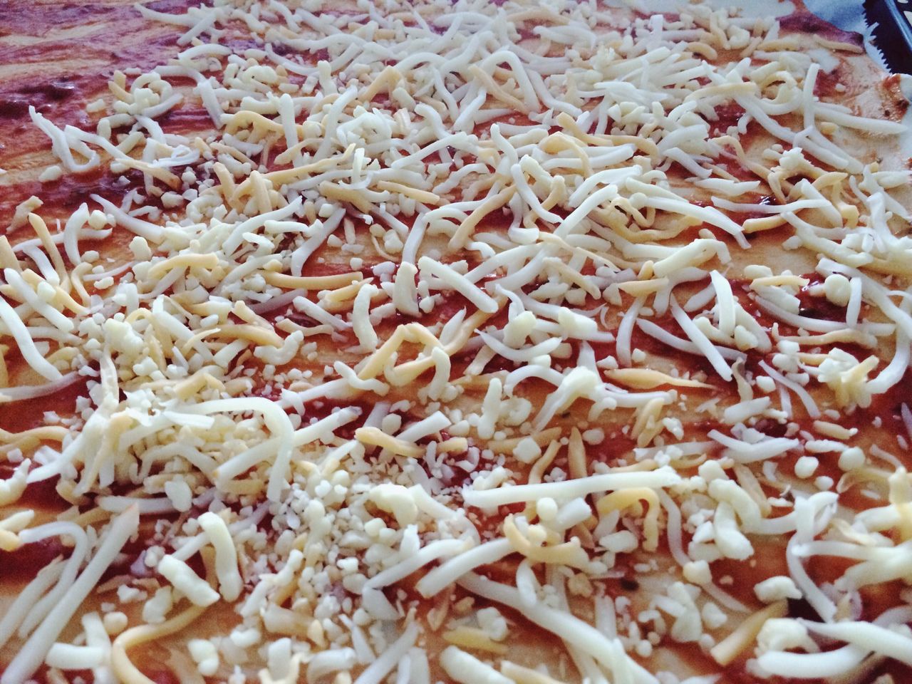 Full frame shot of shredded cheese on pizza bread