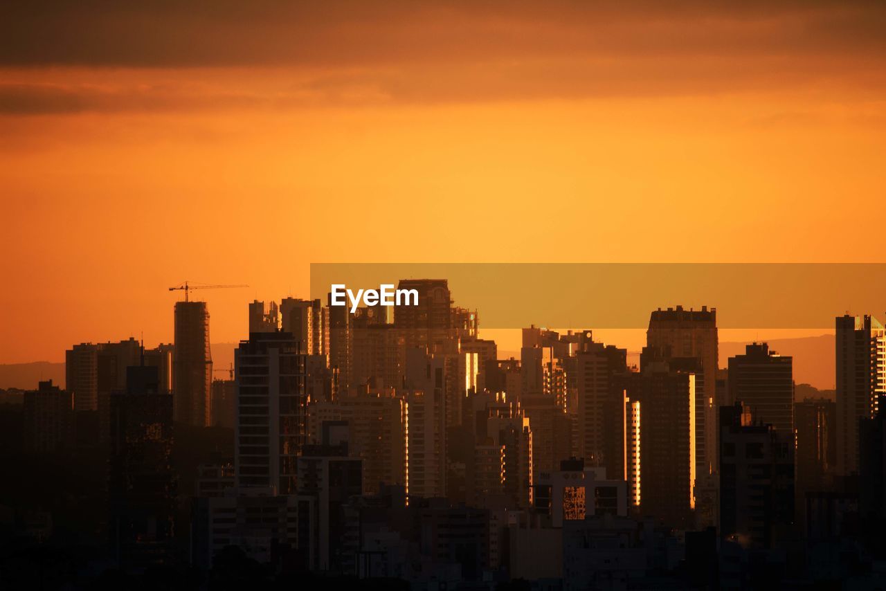 Modern buildings in city against sky during sunset