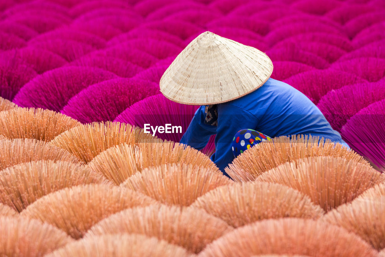 Vietnamese worker surrounded by vibrant bouquets of incense sticks.  cultures around the world.
