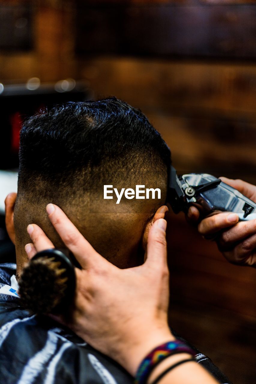 Cropped hand of barber cutting hair