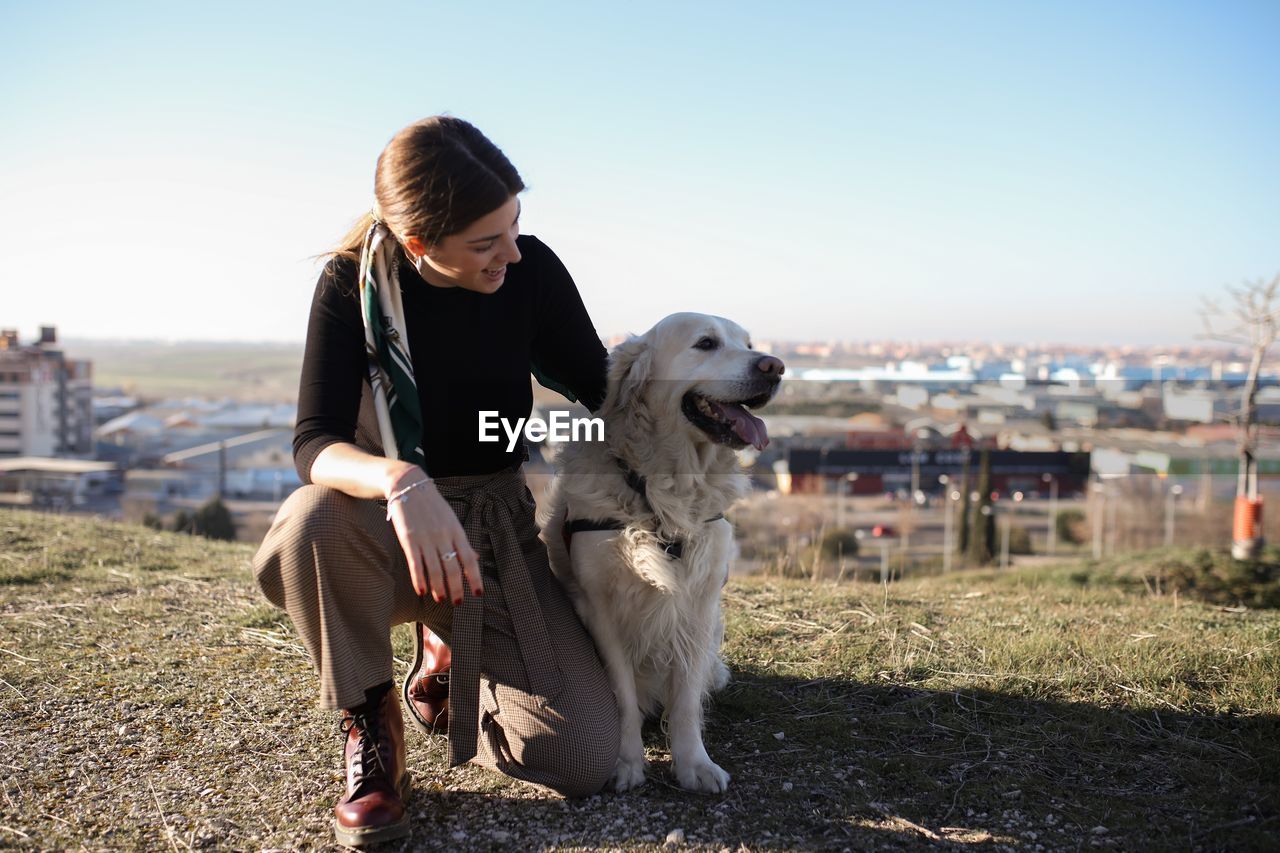 WOMAN WITH DOG AGAINST SKY AT PARK