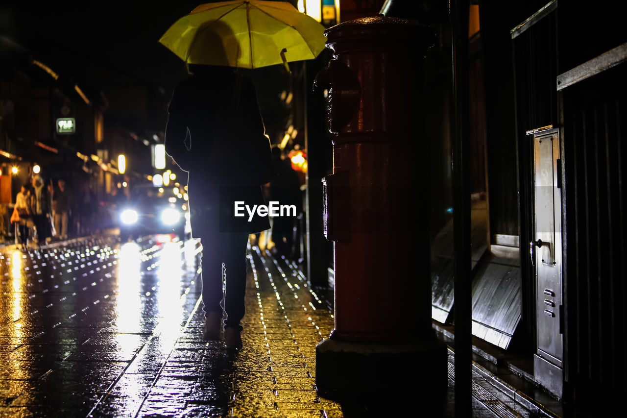 REAR VIEW OF A MAN AT ILLUMINATED NIGHT