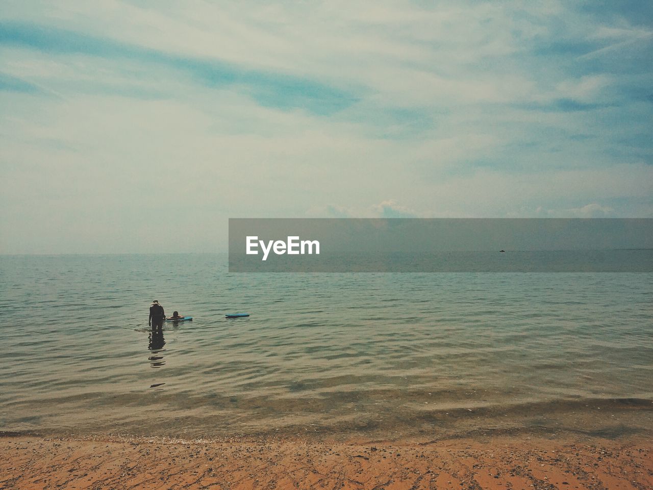 Man standing in sea against cloudy sky