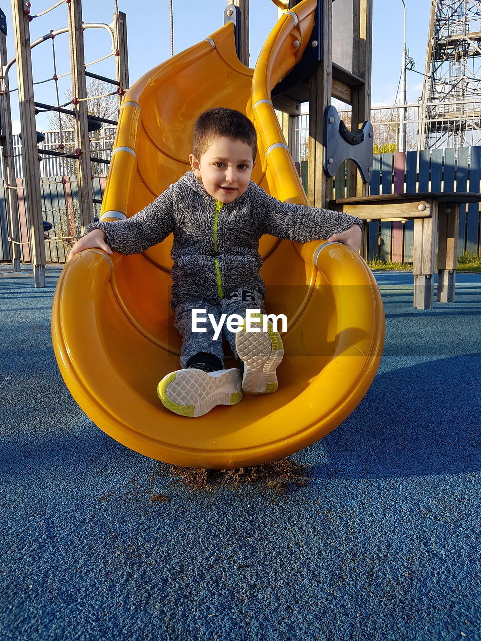 Portrait of boy sitting on slide at playground