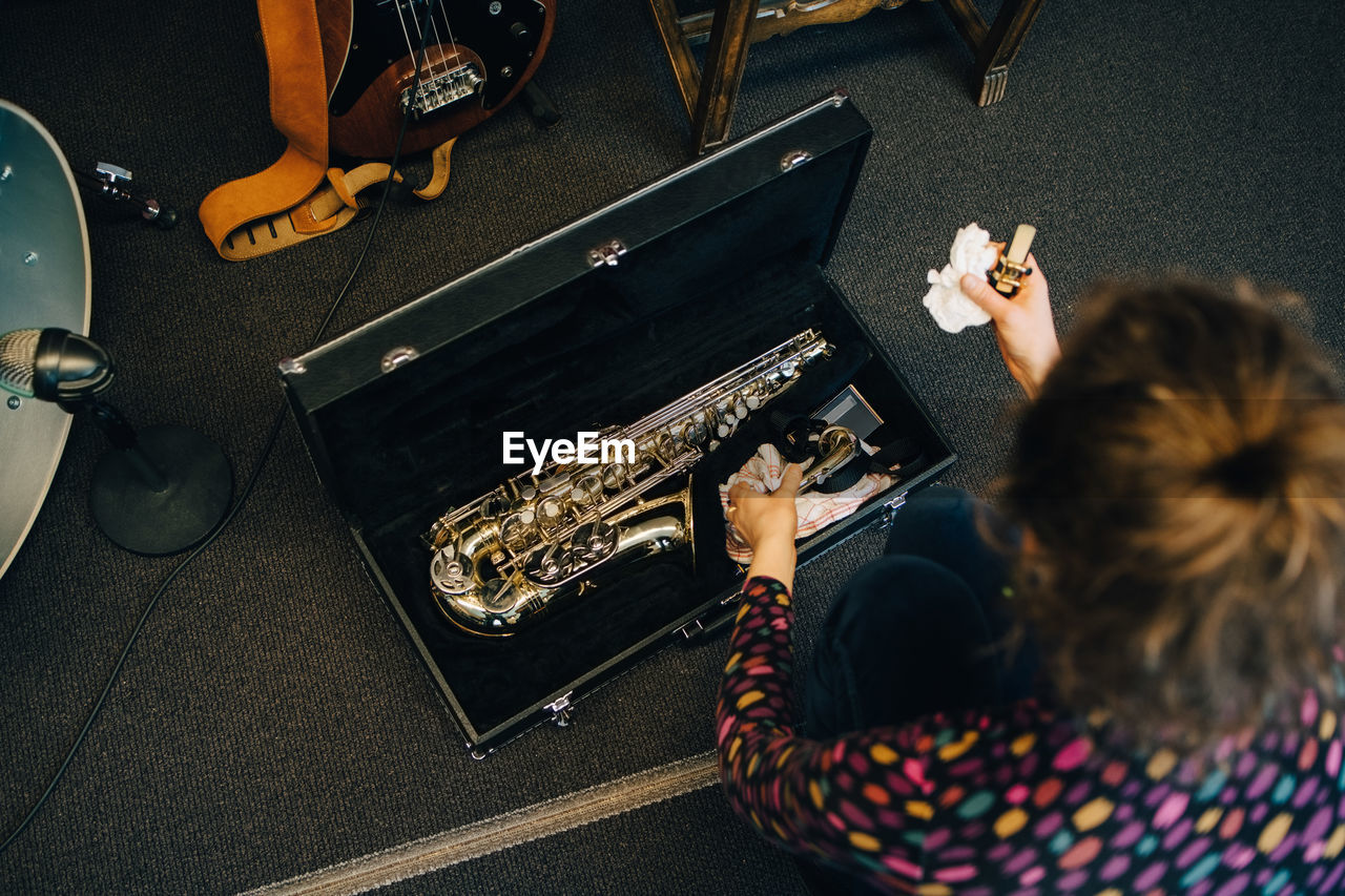 High angle view of woman keeping saxophone in case at studio