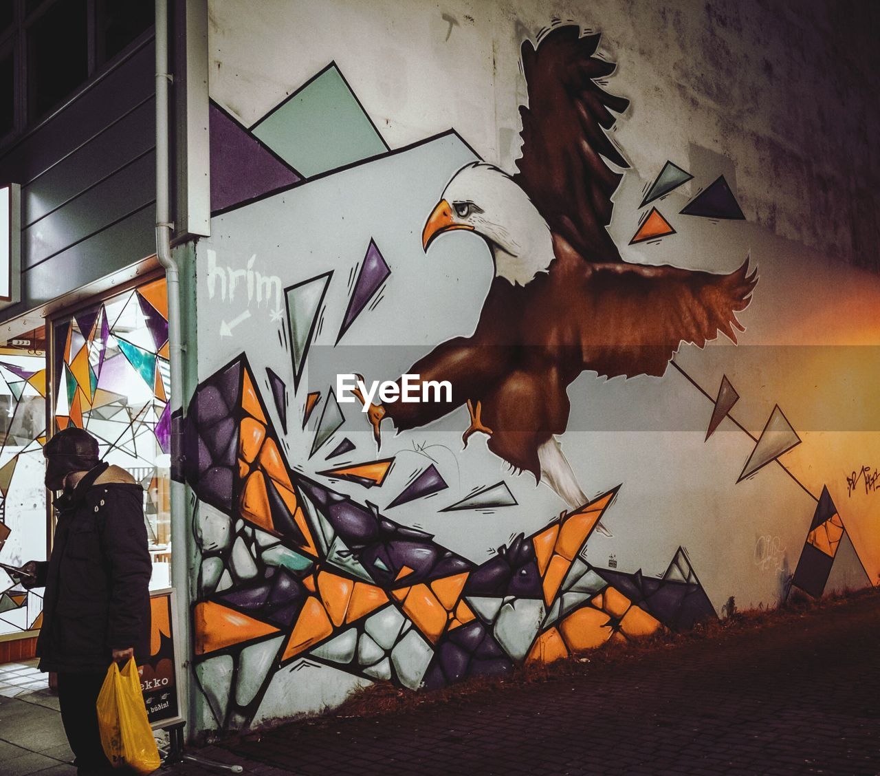 Man standing by graffiti wall on street