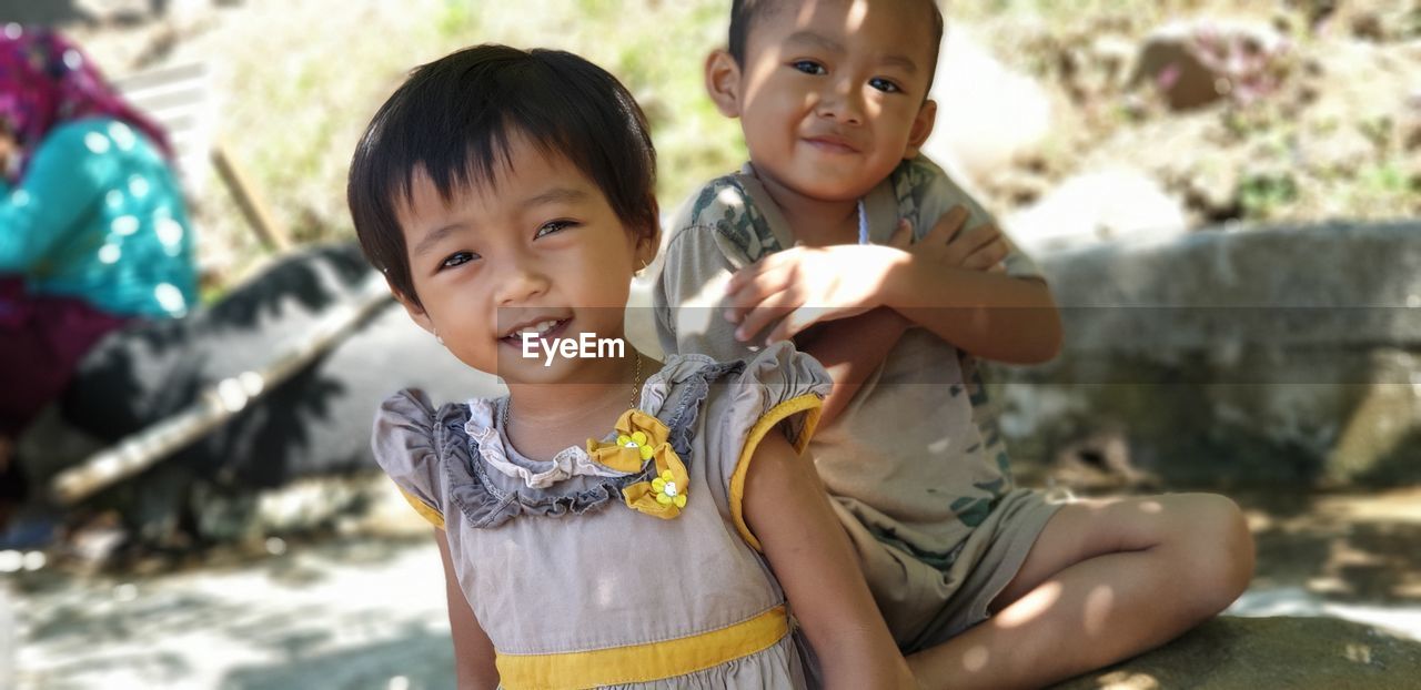 Portrait of siblings smiling on footpath