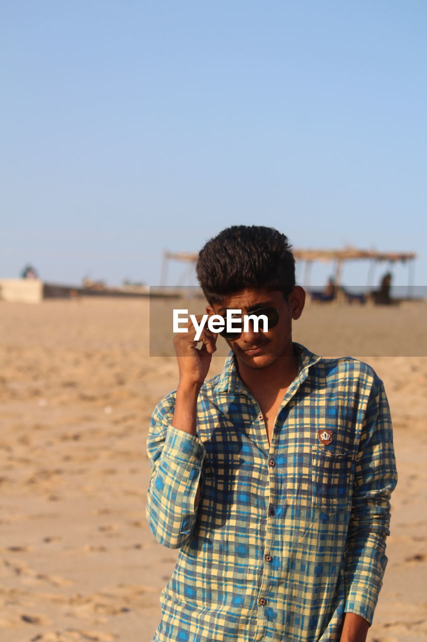 MAN WEARING SUNGLASSES STANDING ON BEACH
